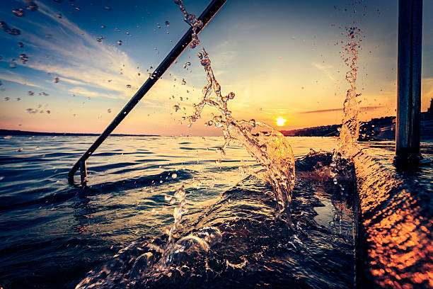 Water splashes from a boat on a beautiful sunset lake, ready for a fishing rod.