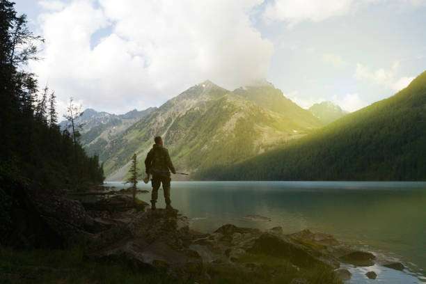 Man enjoying nature by a mountain lake with a fishing rod, ready to cast.