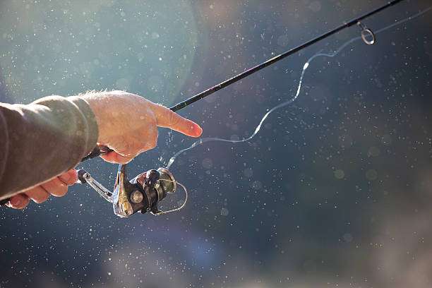 Fisherman's hand holding fishing reel with rod