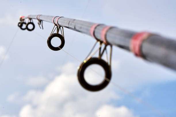 Close-up of fishing rod guides against cloudy sky.