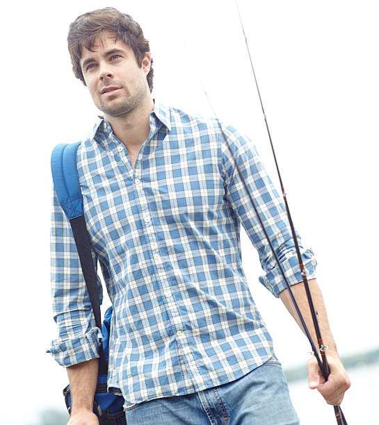 Young man with a backpack holding his fishing rod, ready for fishing.